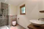 This modern bathroom features a sleek shower, a stylish vessel sink, and a comfortable toilet.