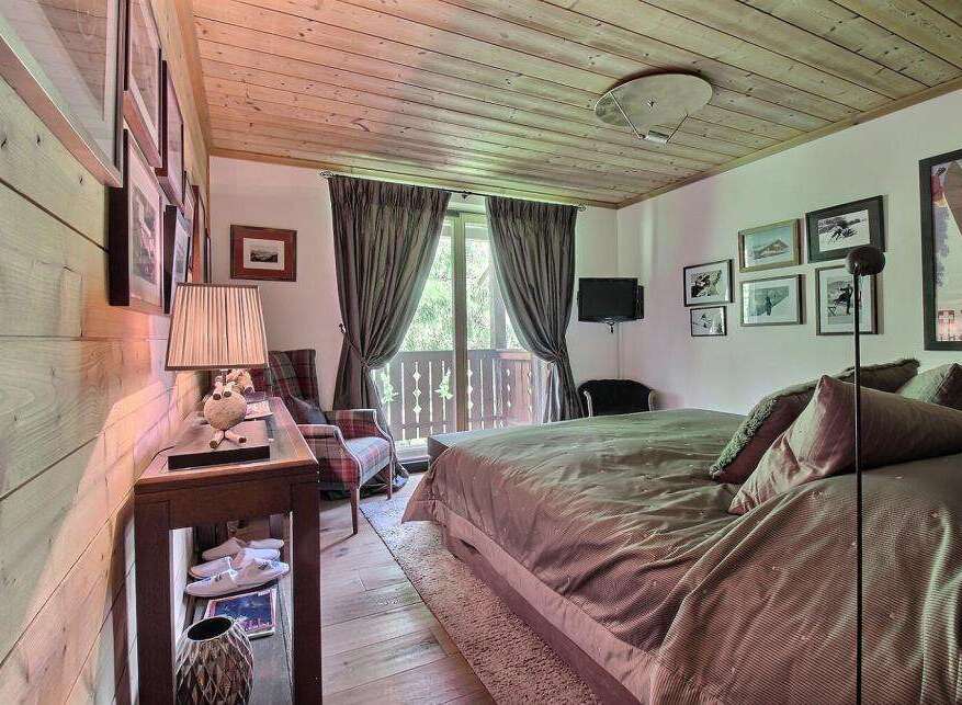 This cozy bedroom features a rustic wooden ceiling and walls, creating a warm and inviting atmosphere.