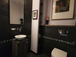 This modern bathroom boasts a sleek design with dark tile walls and flooring, creating a sophisticated ambiance.