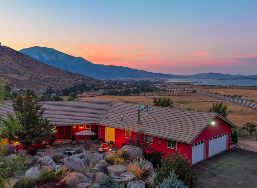 This stunning property boasts a vibrant red exterior and a charming patio area, perfect for enjoying the breathtaking sunset views.