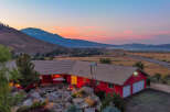 This stunning property boasts a vibrant red exterior and a charming patio area, perfect for enjoying the breathtaking sunset views.