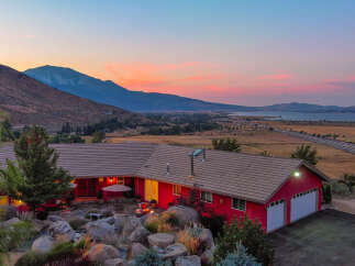 This stunning property boasts a vibrant red exterior and a charming patio area, perfect for enjoying the breathtaking sunset views.