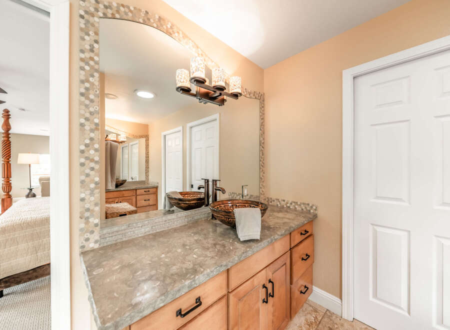 This beautiful bathroom features a stylish vanity with a unique vessel sink and a stunning mosaic mirror frame.