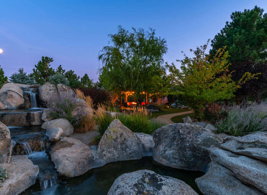 Experience tranquility in this stunning property featuring a serene waterfall cascading over natural rock formations.