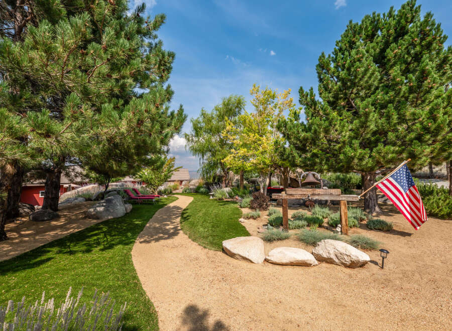 This stunning property boasts a beautifully landscaped yard with lush greenery and a winding pathway.