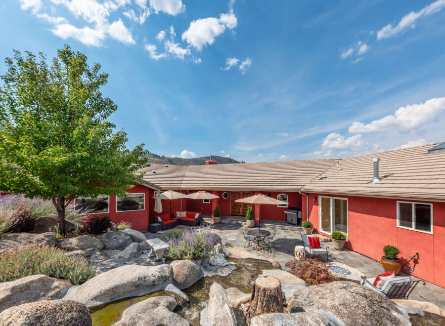 This stunning property boasts a beautifully landscaped backyard with a serene water feature and lush greenery.