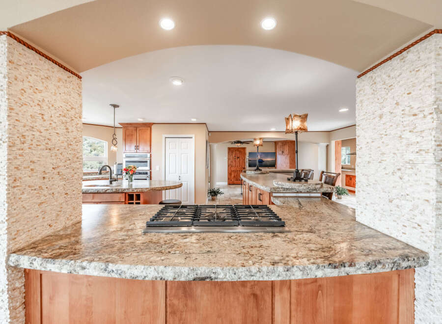 Step into this stunning kitchen, showcasing a beautiful granite countertop and a modern gas cooktop.