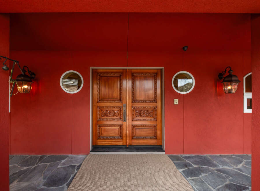 This stunning property boasts a grand entrance with intricately carved wooden double doors, creating a welcoming first impression.