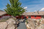 This stunning property boasts a vibrant red exterior, complemented by a lush green tree and natural rock formations.