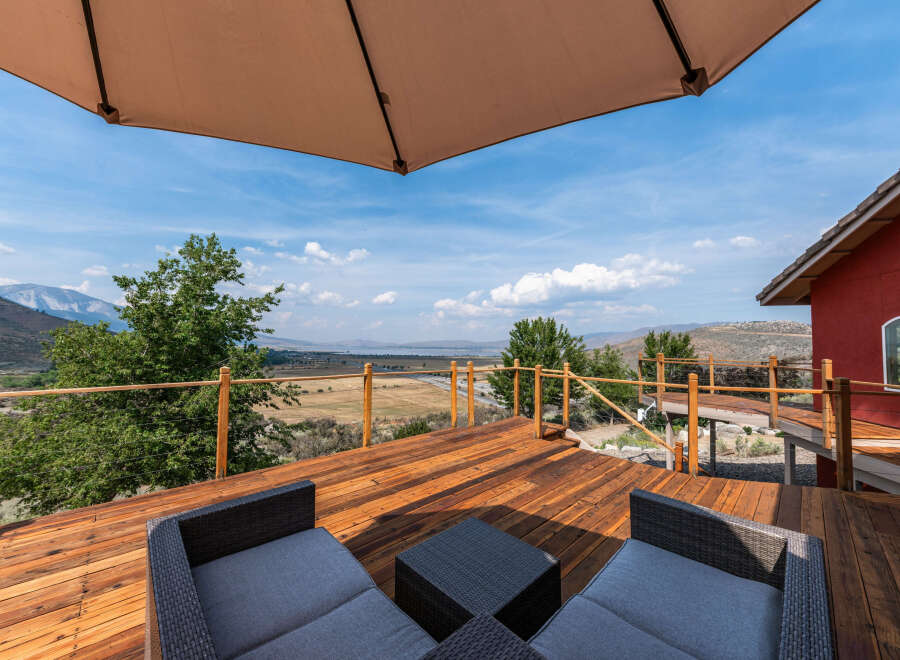 Enjoy breathtaking views from this stunning property featuring a spacious wooden deck and comfortable outdoor seating.