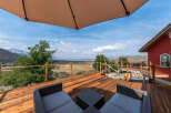 Enjoy breathtaking views from this stunning property featuring a spacious wooden deck and comfortable outdoor seating.