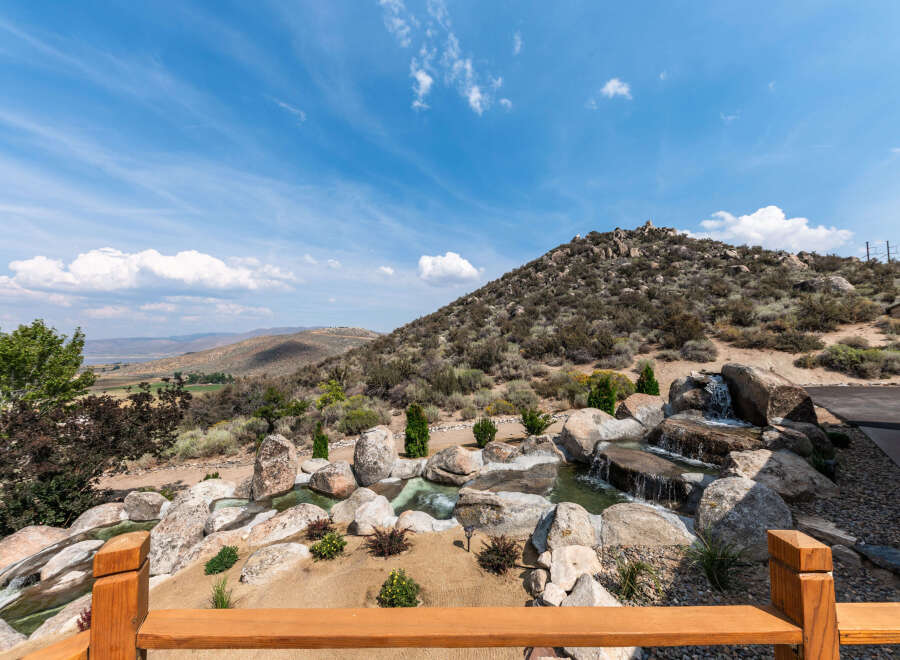 Experience the tranquility of this stunning property, featuring a beautifully designed water feature that cascades over natural rock formations.