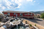 Discover a stunning red-hued home nestled in a picturesque landscape, complete with a cascading waterfall feature.