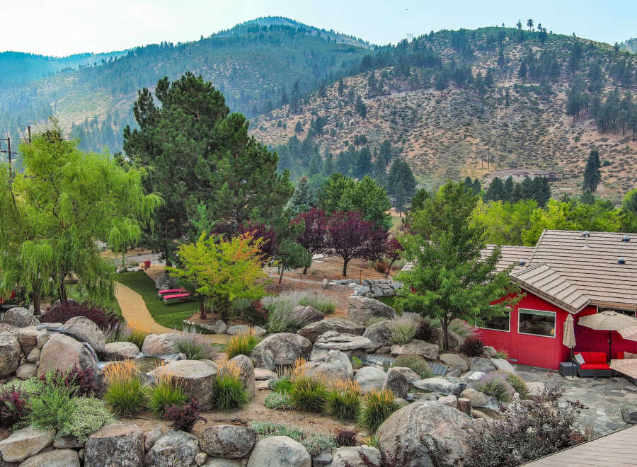 This stunning property boasts a beautifully landscaped yard with lush greenery and a serene rock garden.