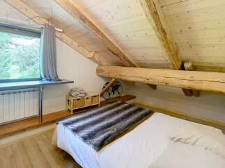 Discover the charm of this cozy bedroom, featuring a unique wooden beam ceiling that adds character and warmth.