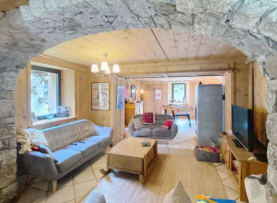 Discover the charm of this inviting living space, featuring a cozy ambiance with wooden accents and a stone archway.