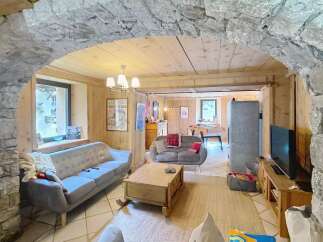 Discover the charm of this inviting living space, featuring a cozy ambiance with wooden accents and a stone archway.