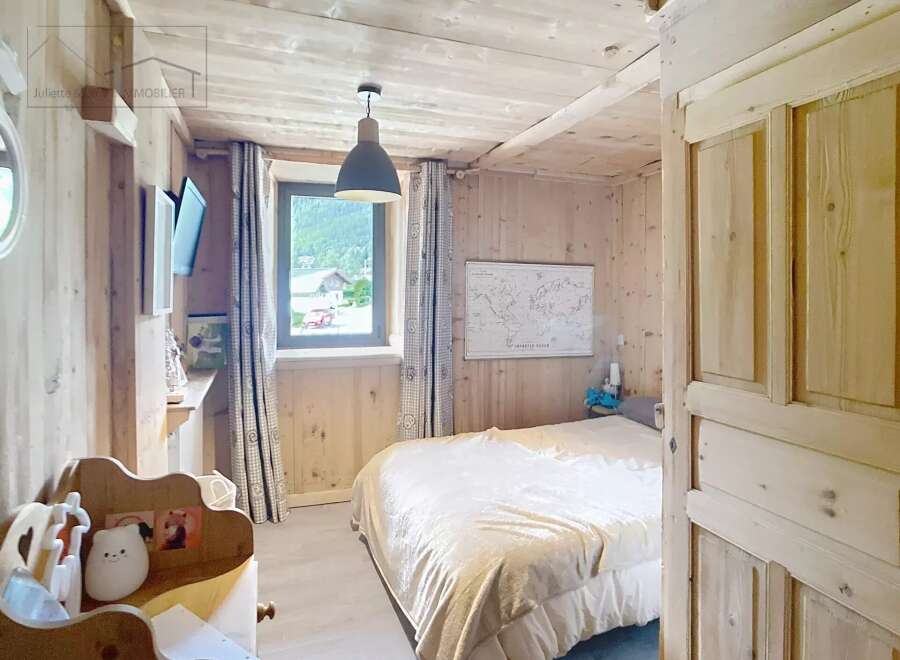 Discover the charm of this cozy bedroom, featuring a warm wooden interior and a comfortable bed.