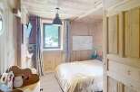 Discover the charm of this cozy bedroom, featuring a warm wooden interior and a comfortable bed.