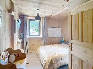 Discover the charm of this cozy bedroom, featuring a warm wooden interior and a comfortable bed.