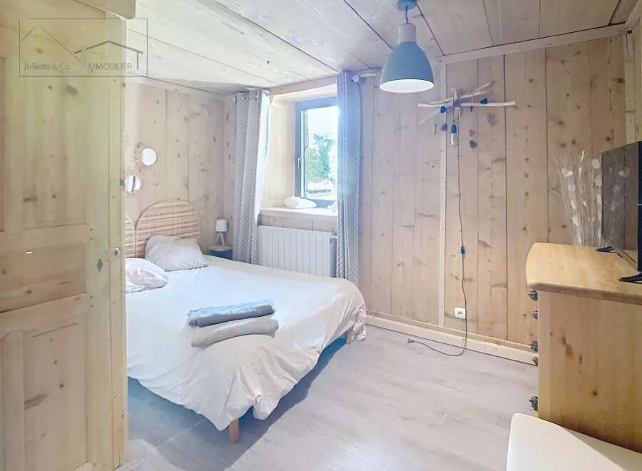 Discover the charm of this cozy bedroom, featuring a warm wooden interior and a comfortable bed.