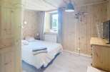 Discover the charm of this cozy bedroom, featuring a warm wooden interior and a comfortable bed.