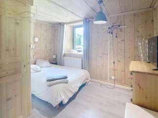 Discover the charm of this cozy bedroom, featuring a warm wooden interior and a comfortable bed.