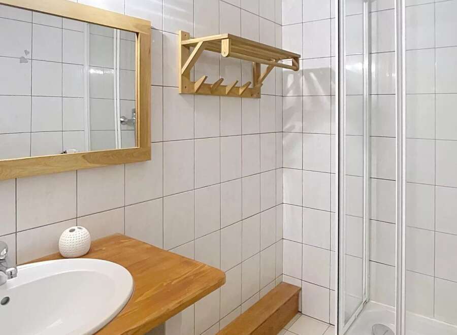 This bathroom features a sleek, modern design with a wooden vanity and a spacious shower.