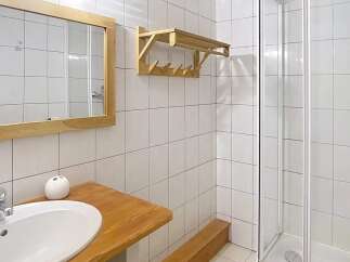 This bathroom features a sleek, modern design with a wooden vanity and a spacious shower.