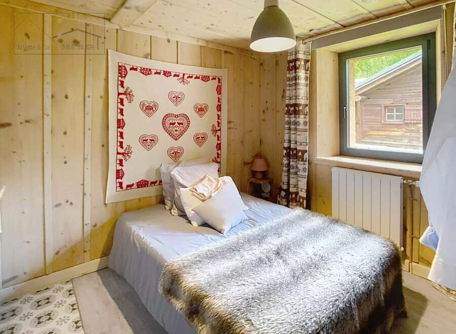 Cozy bedroom with wooden walls and ceiling, creating a warm and inviting atmosphere.