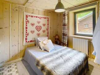 Cozy bedroom with wooden walls and ceiling, creating a warm and inviting atmosphere.
