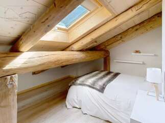 Discover the charm of this cozy bedroom, featuring exposed wooden beams that add character and warmth.