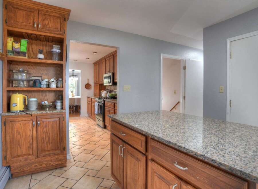 Step into this inviting kitchen, featuring warm wooden cabinetry and a spacious granite countertop island.