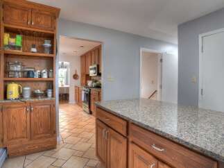 Step into this inviting kitchen, featuring warm wooden cabinetry and a spacious granite countertop island.