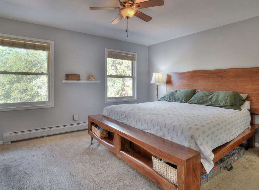 This inviting bedroom features a stunning wooden headboard and a unique bench at the foot of the bed, offering both style and functionality.
