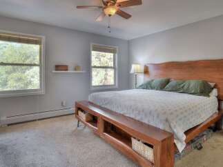 This inviting bedroom features a stunning wooden headboard and a unique bench at the foot of the bed, offering both style and functionality.