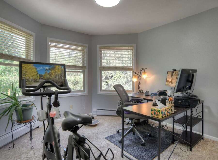 This home office space seamlessly blends work and wellness, featuring a Peloton bike for convenient workouts.