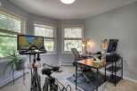 This home office space seamlessly blends work and wellness, featuring a Peloton bike for convenient workouts.