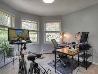 This home office space seamlessly blends work and wellness, featuring a Peloton bike for convenient workouts.