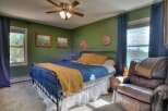 This cozy bedroom features a comfortable bed with a vibrant blue comforter and a warm yellow throw, creating a welcoming atmosphere.