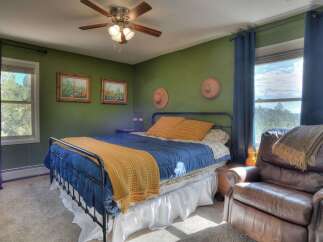 This cozy bedroom features a comfortable bed with a vibrant blue comforter and a warm yellow throw, creating a welcoming atmosphere.