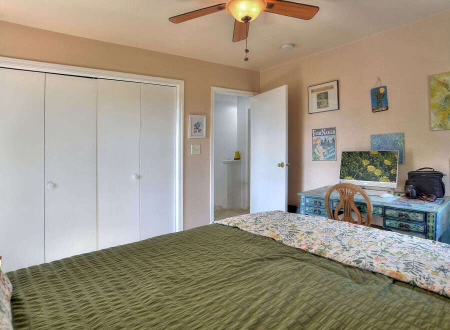 This inviting bedroom features a comfortable bed with a stylish green comforter and a floral patterned throw.