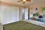 This inviting bedroom features a comfortable bed with a stylish green comforter and a floral patterned throw.