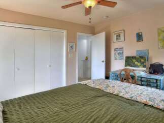 This inviting bedroom features a comfortable bed with a stylish green comforter and a floral patterned throw.