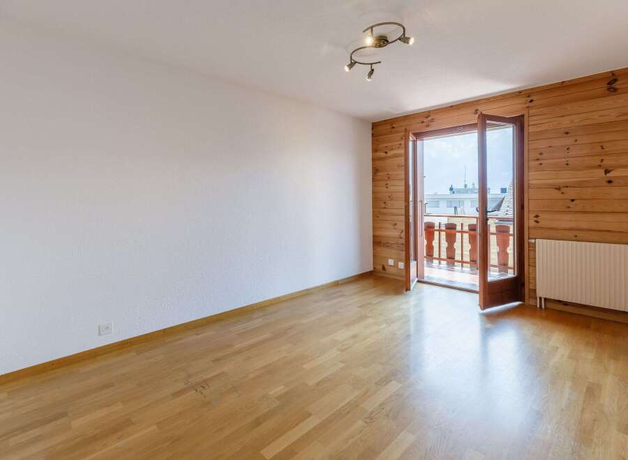 This bright and airy room features beautiful wooden floors and a stunning wooden accent wall.