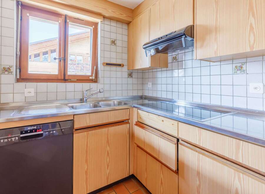 This charming kitchen features a warm, inviting design with wooden cabinetry and a stainless steel countertop.