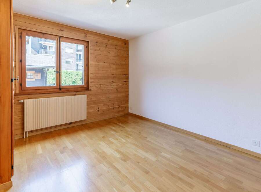 This inviting room features a warm wooden wall and a bright window, creating a cozy atmosphere.