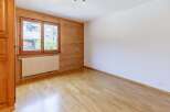 This inviting room features a warm wooden wall and a bright window, creating a cozy atmosphere.
