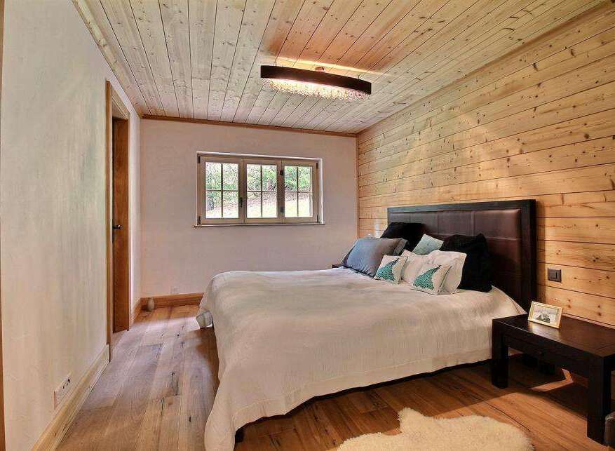 This cozy bedroom features a warm, inviting atmosphere with its wooden walls and ceiling.
