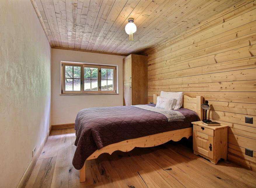This cozy bedroom features a rustic design with wooden walls and flooring, creating a warm and inviting atmosphere.